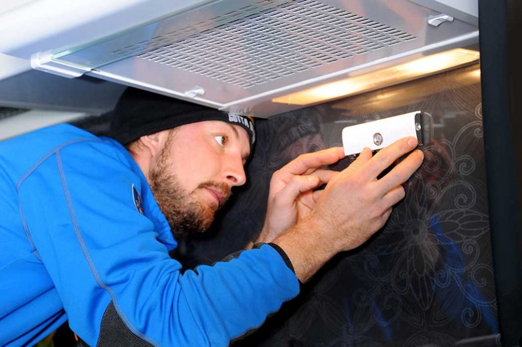 An electrician installing a Safera Airis stove guard under the cooker hood